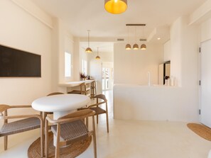 A modern kitchen with white cabinetry, a dining area with a white table and wooden chairs, and pendant lighting. - Penthouse with exclusive terrace, pool, and panoramic views (Málaga)