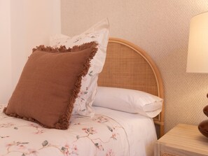 A bed with a floral bedspread, a brown textured pillow, and a white pillow with a floral pattern. - Elegant and bright three-bedroom, two-bathroom apartment (Málaga)