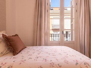 A bedroom with a bed, curtains, and a view of a balcony. - Elegant and bright three-bedroom, two-bathroom apartment (Málaga)