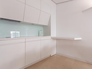 A modern kitchen with white cabinetry, a stainless steel range hood, and a light blue backsplash. - Balcones de San Juan (Málaga)