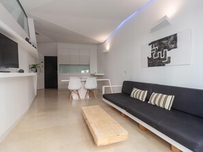 A modern living room with a black sofa, wooden coffee table, and white chairs. - Balcones de San Juan (Málaga)