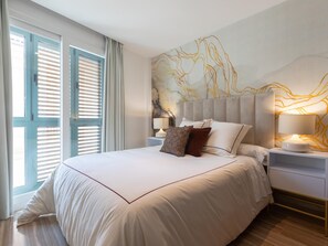 A modern bedroom with a large bed, two bedside tables with lamps, and a wall with a marble-like pattern. - Bright apartment with views of Uncibay Square (Málaga)