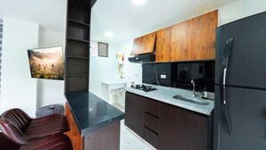 Una cucina moderna con mobili scuri, un frigorifero in acciaio inossidabile e una stufa a gas.