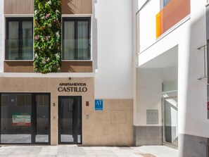 Un immeuble avec une enseigne indiquant « APARTAMENTOS CASTILLO » et un symbole bleu « AT » signalant l’accessibilité aux personnes handicapées.