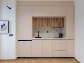 A modern kitchen with a wooden upper cabinet, a black countertop, and a marble backsplash. - Bright studio in a building with terrace (Málaga)