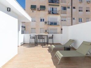 A rooftop terrace with a table and chairs, a small table, and two lounge chairs. - Bright studio in a building with terrace (Málaga)