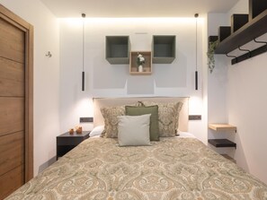 Ein Schlafzimmer mit einem Bett, Nachttischen, einem Holzschrank, einer hängenden Pflanze und Einbauschränken.