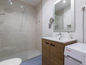 Ein modernes Badezimmer mit Duschkabine aus Glas, einem weißen Waschbecken und einem Spiegel darüber.