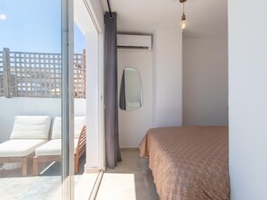 Ein Schlafzimmer mit einem Bett, einem Spiegel, einem Fenster und einem Deckenventilator.