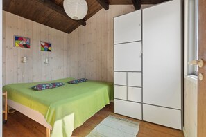 Ein Zimmer mit einem Bett, einem Kleiderschrank, Holzwänden und einer Deckenleuchte.