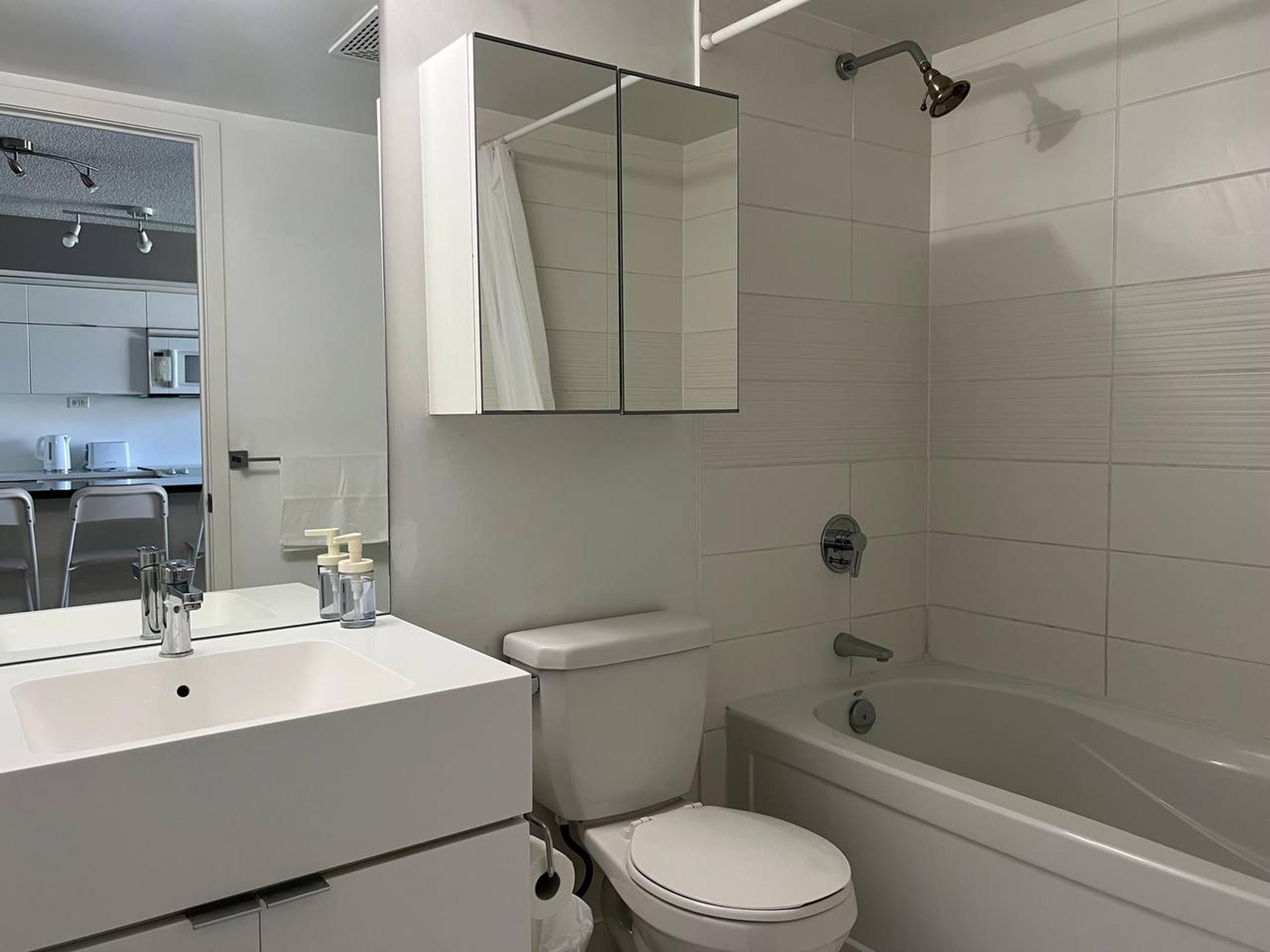 A modern bathroom with a white sink, toilet, and bathtub.