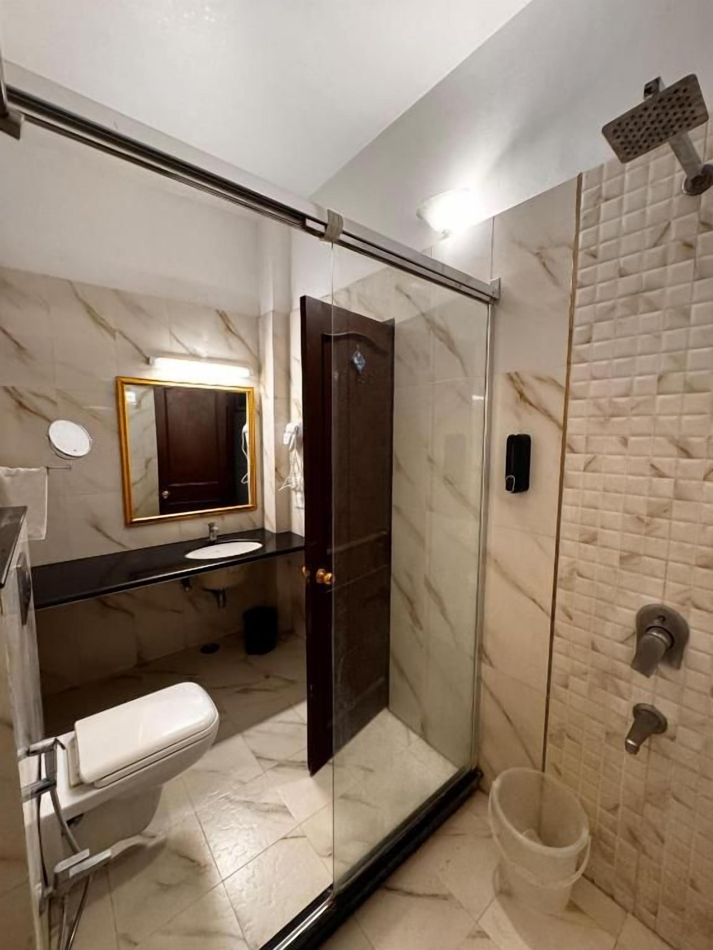 Ein modernes Badezimmer mit einer Duschkabine, Toilette, Waschbecken und Spiegel.