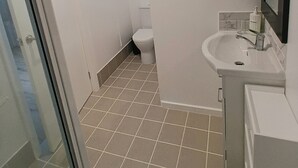 A small bathroom with a toilet, sink, and a window. - Twin Beaches Arrawarra Headland (Arrawarra Headland)