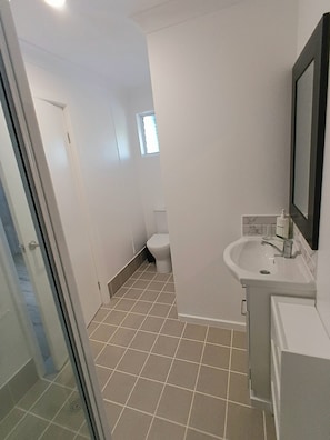 Et lille badeværelse med toilet, vask og et vindue.