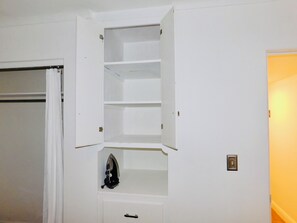 A white interior space with a built-in shelving unit, a door with a curtain, and a wall-mounted light switch. - Upgraded Quiet 1 bed, 1 bath Share home, mins to UofA, Downtown & Shopping (Tucson)