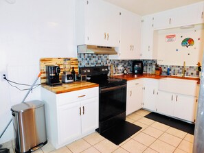 A modern kitchen with white cabinets, a wooden countertop, a black stove, and a coffee maker. - Upgraded Quiet 1 bed, 1 bath Share home, mins to UofA, Downtown & Shopping (Tucson)