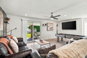 A modern living room with a pool table, leather sofa, and a ceiling fan. - 4-bedroom Retreat in Scottsdale with Heated Pool, Firepit, Putting Green/Games (Scottsdale)