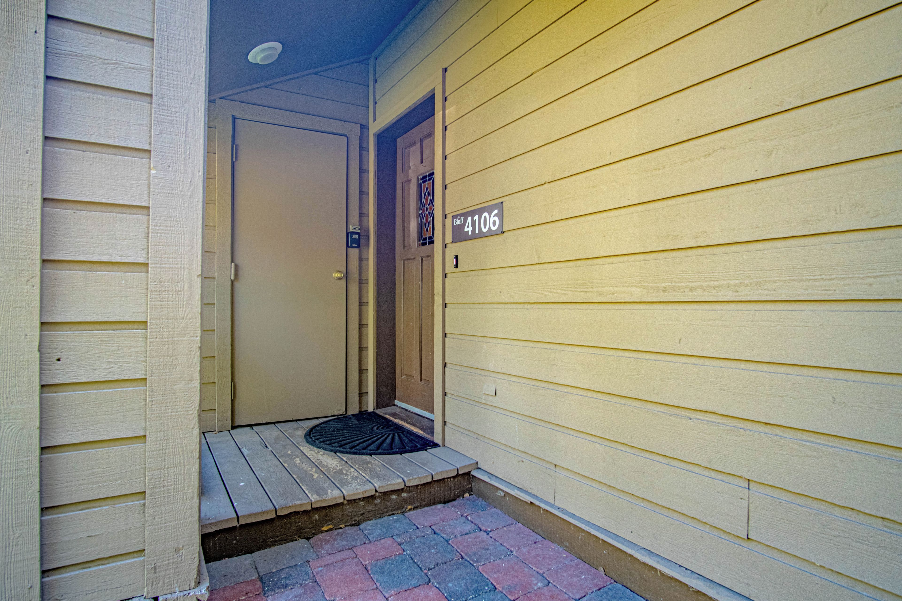 A front door with a number plaque, a small porch with a doormat, and a mailbox.