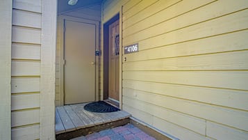 A front door with a number plaque, a small porch with a doormat, and a mailbox.
