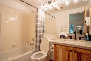 A bathroom with a bathtub, toilet, and a sink with a mirror above it. - 3BR Elkhorn Village condo with pool, hot tub, fireplace, and mountain access. (Sun Valley)