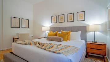A neatly arranged hotel room with a large bed, bedside tables, a chair, and a desk.