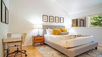 A bedroom with a bed, bedside tables, a desk, and a chair.