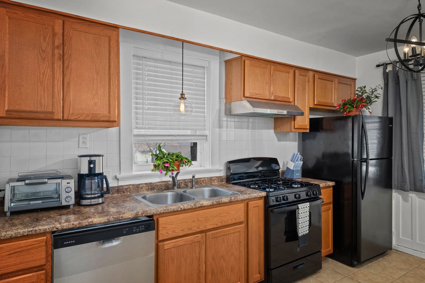 A kitchen with wooden cabinets, a stainless steel refrigerator, a stove, a dishwasher, and a coffee maker.