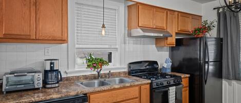 A kitchen with wooden cabinets, a stainless steel refrigerator, a stove, a dishwasher, and a coffee maker.