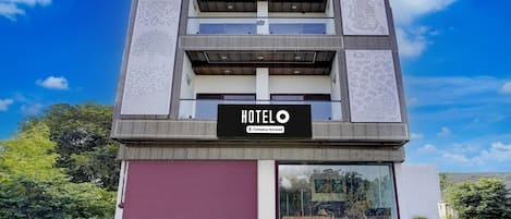 Un hotel moderno con un cartel llamativo que dice 'HOTEL', un toldo de garaje rojo y un balcón con barandilla metálica.