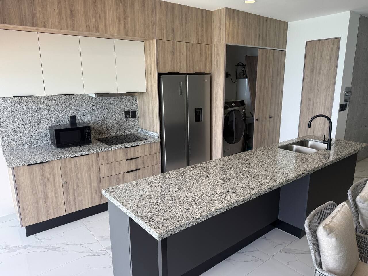 A modern kitchen with granite countertops, stainless steel appliances, and wooden cabinetry.