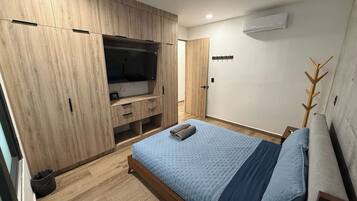 Een slaapkamer met een bed, een kledingkast en een televisie.