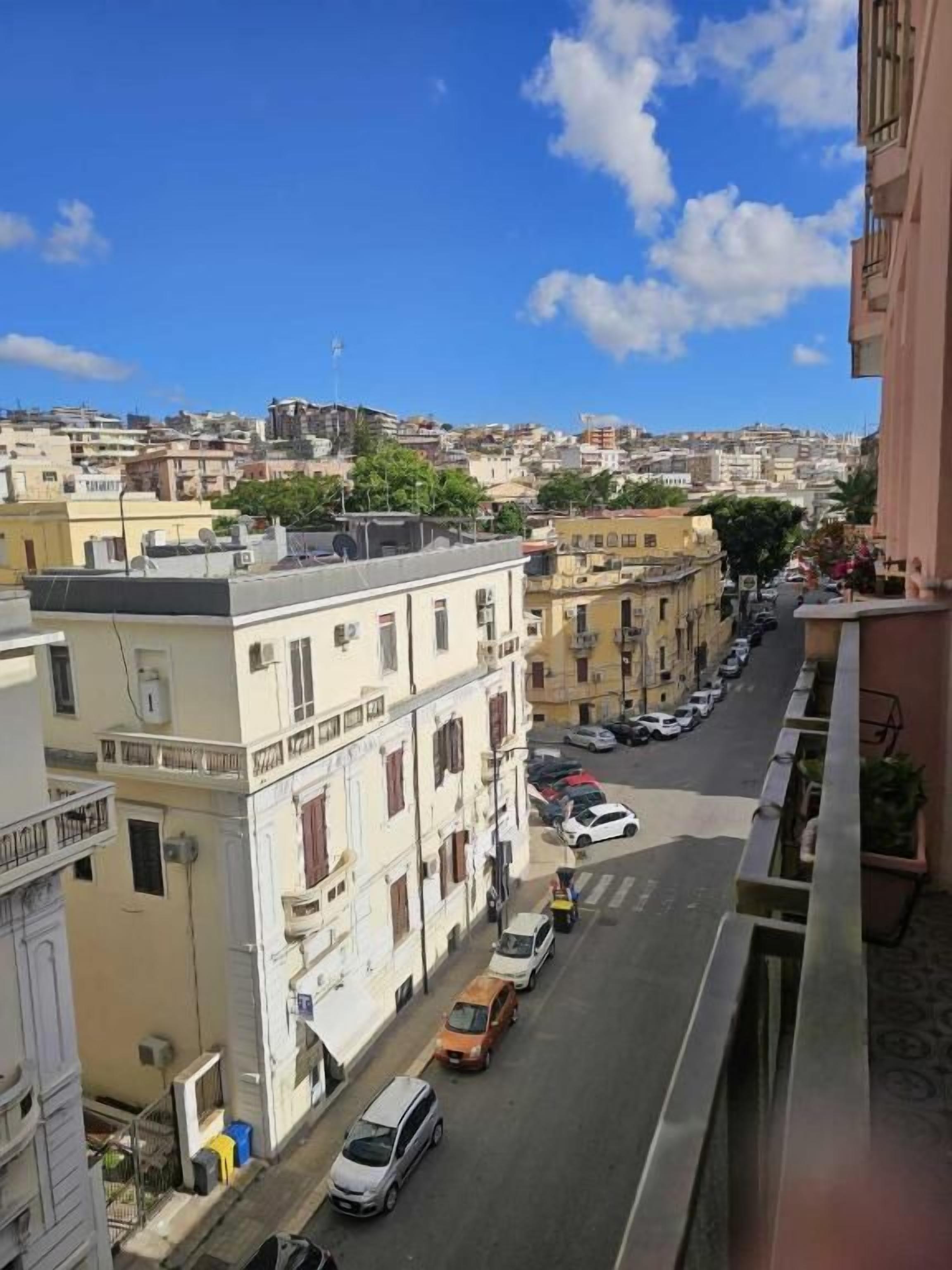 A street view with buildings, parked cars, and a clear sky.