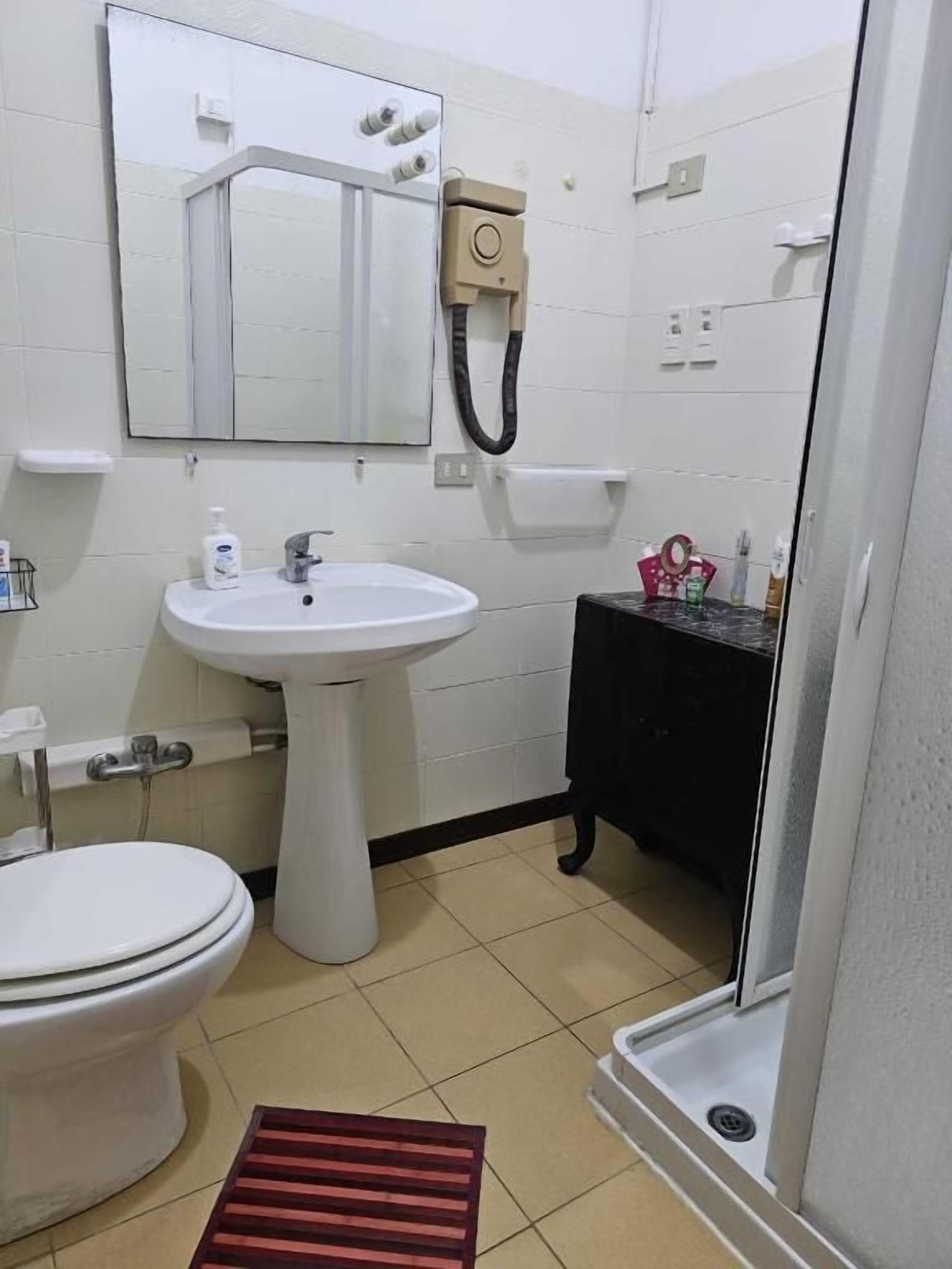 Un bagno con il water, lavandino, specchio e doccia.