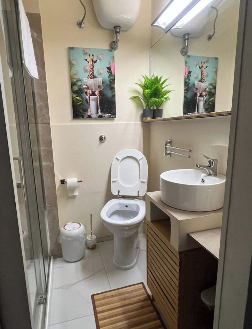 Ein Badezimmer mit Toilette, Waschbecken, Spiegel und einem kleinen Blumentopf.