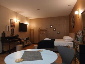 Una habitación de hotel con una cama, un escritorio, una silla, un televisor y una mesa redonda.