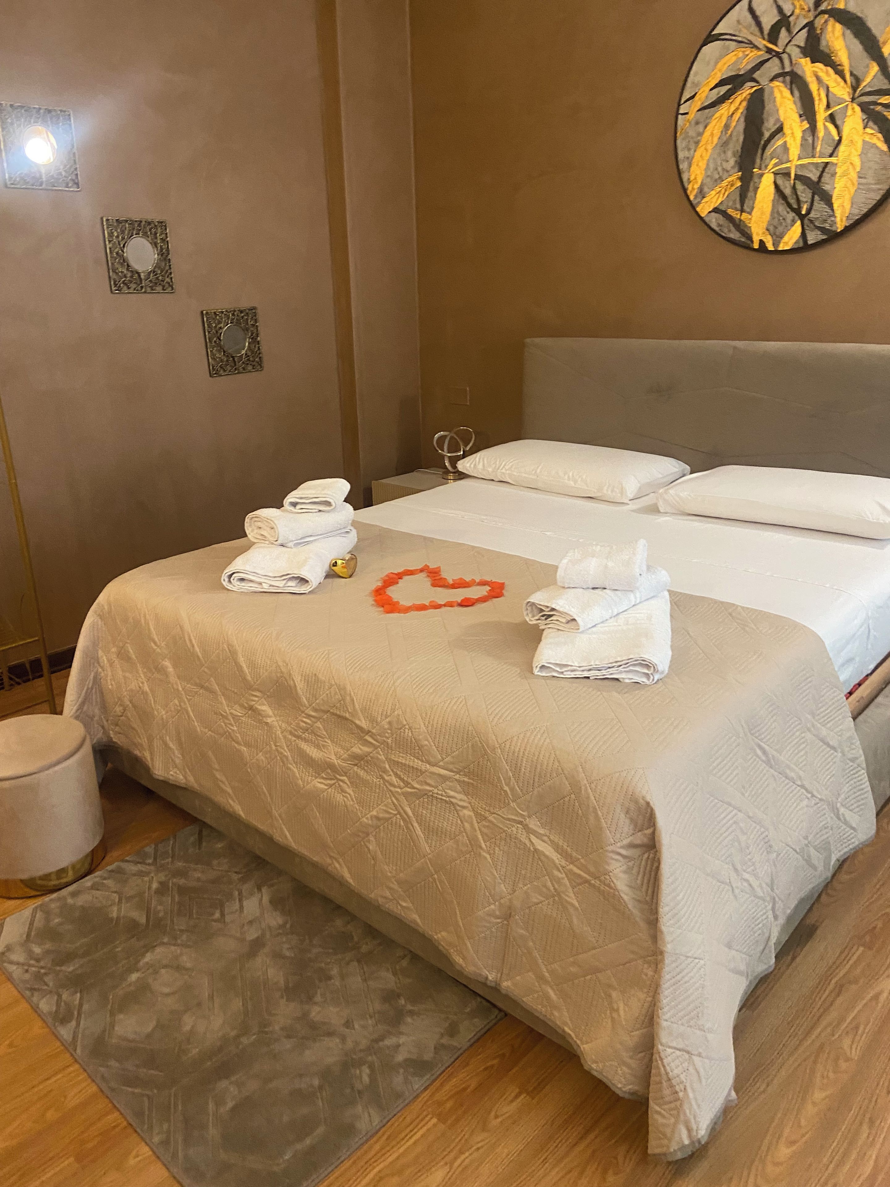 Una habitación de hotel con una cama, dos almohadas, una decoración con forma de corazón y toallas.