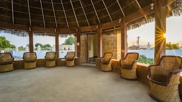 An outdoor seating area with wicker chairs and a thatched roof.