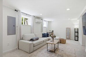 A modern living room with a sofa, a coffee table, and a TV stand. - Modern 4BR Home - Parking - Close to Downtown (Seattle)