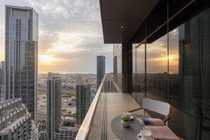 Ein Hochhaus mit einem Balkon, der auf eine städtische Szenerie im Abendrot blickt.