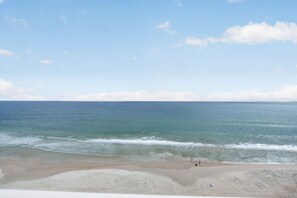 A beach with calm waves and a clear sky. - Serenity at The Opus (Daytona Beach)