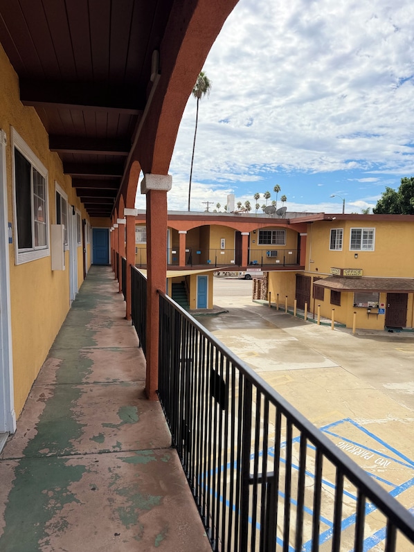 A corridor with a balcony, a building with multiple windows, and a clear sky.