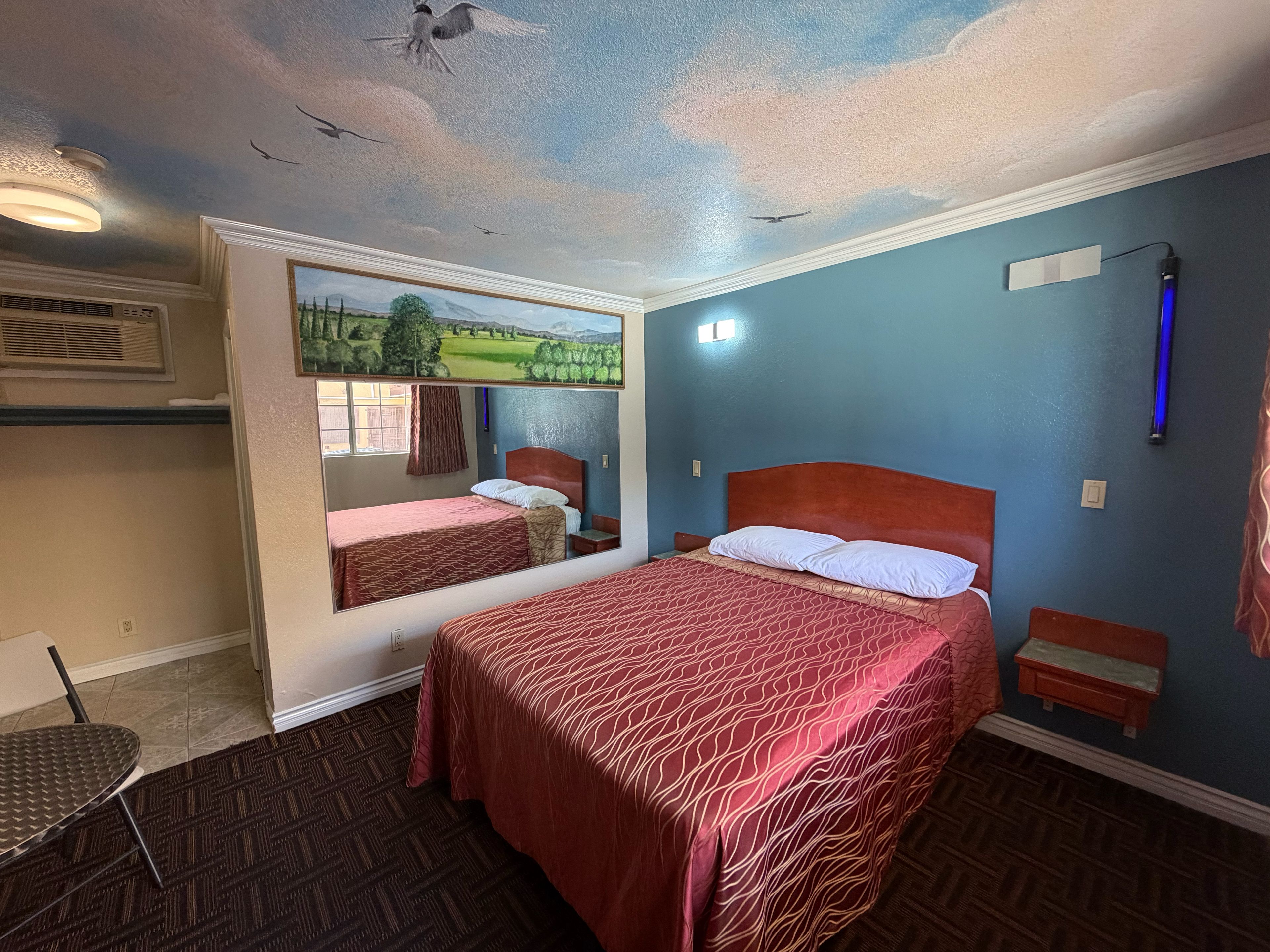Ein Hotelzimmer mit einem großen Bett, einem kleineren Bett, einem Schreibtisch und einem Sessel.