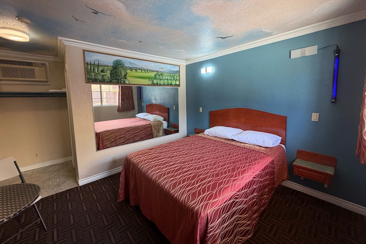 A hotel room with a large bed, a smaller bed, a desk, and a chair.