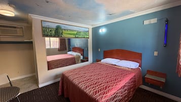 Ein Hotelzimmer mit einem großen Bett, einem kleineren Bett, einem Schreibtisch und einem Sessel.