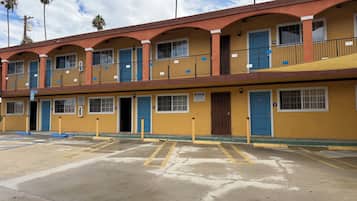 Um motel com várias divisões, estacionamento e céu limpo.