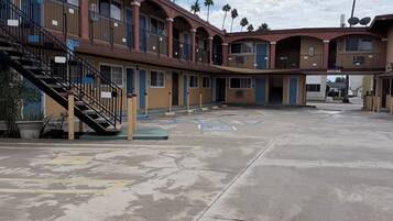 A motel with multiple floors, outdoor parking, and palm trees.