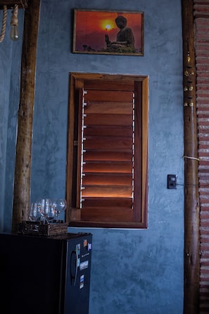 A room with a wooden door, a wall-mounted picture of a Buddha, and a refrigerator with magnets.