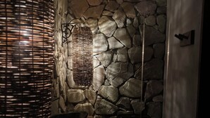 Un bagno con parete in pietra, lampadario in fibra naturale e lavandino moderno.