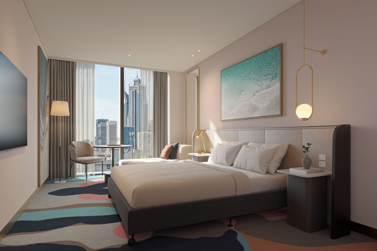 Une chambre d’hôtel moderne, dotée d’un grand lit, d’un bureau, d’une chaise et offrant une vue sur le panorama urbain.