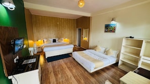 A hotel room with a bed, a desk with a computer, a TV, and a bookshelf. - The Sky Hotels (Mussoorie)